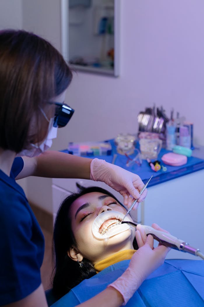Dentist examining patient's teeth with tools in a modern clinic setting.